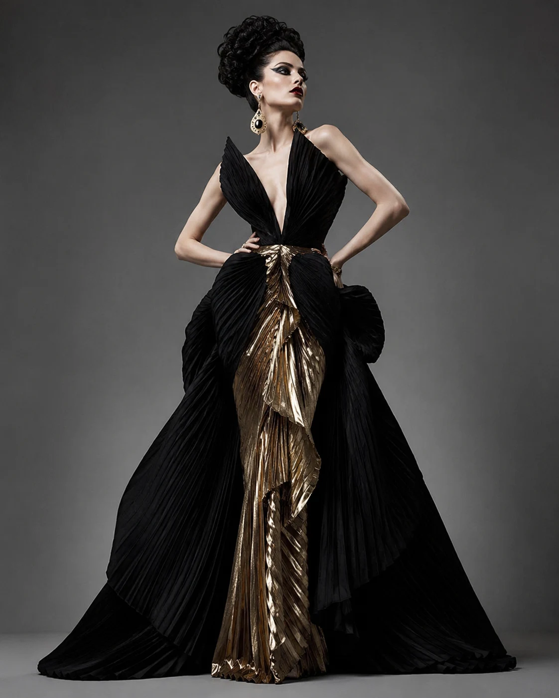 Dramatic style archetype: woman in sculptural black pleated gown with gold lining, arms out