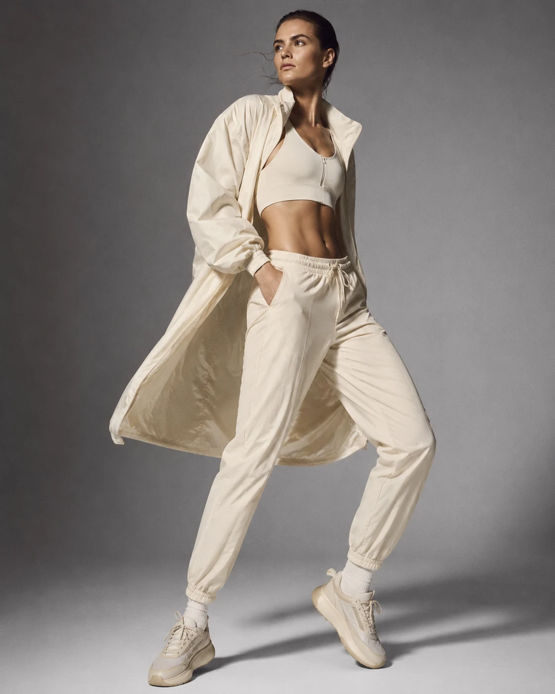 Sporty style archetype: woman in cream tracksuit, crop top and sneakers